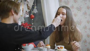 一位年轻的少女，棕色头发，坐在一家青年咖啡馆里，<strong>一个</strong>年轻人用<strong>勺子</strong>品尝美味的甜点